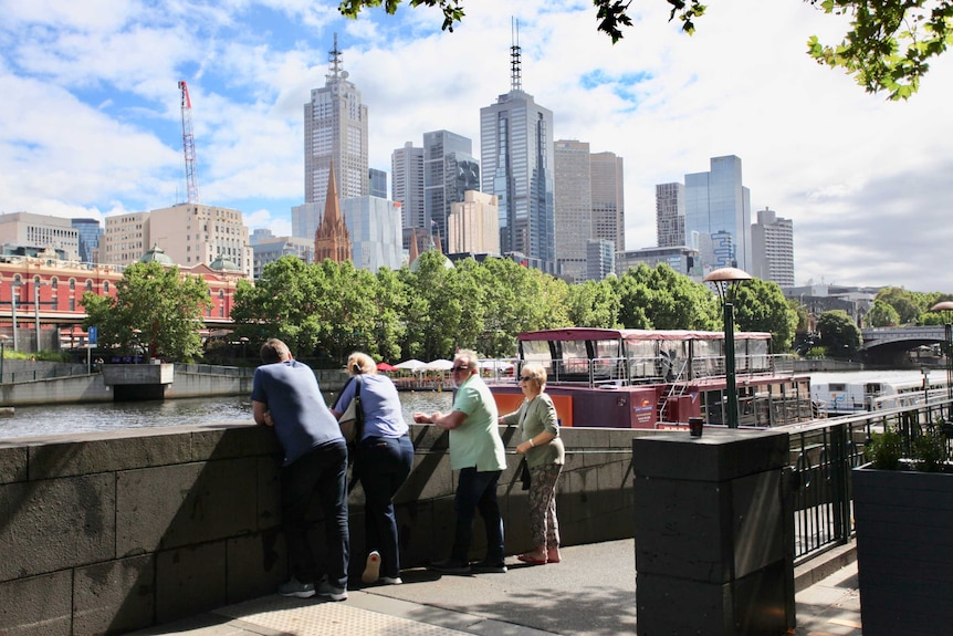 Four people look at the Yarra River with the CBD skyline in the background.