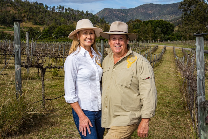 Woman and man in front of vineyard rows.