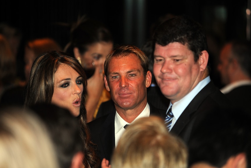 Elizabeth Hurley, Shane Warne and James Packer in a crowded room.