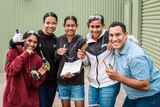 Science communicator Torres Webb and a group of indigenous students with smiles on their faces