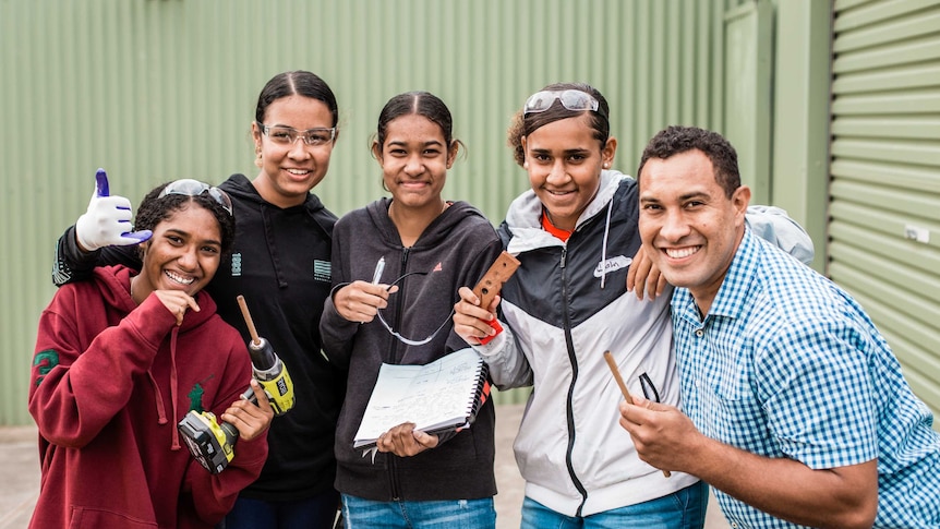 Science communicator Torres Webb and a group of indigenous students with smiles on their faces