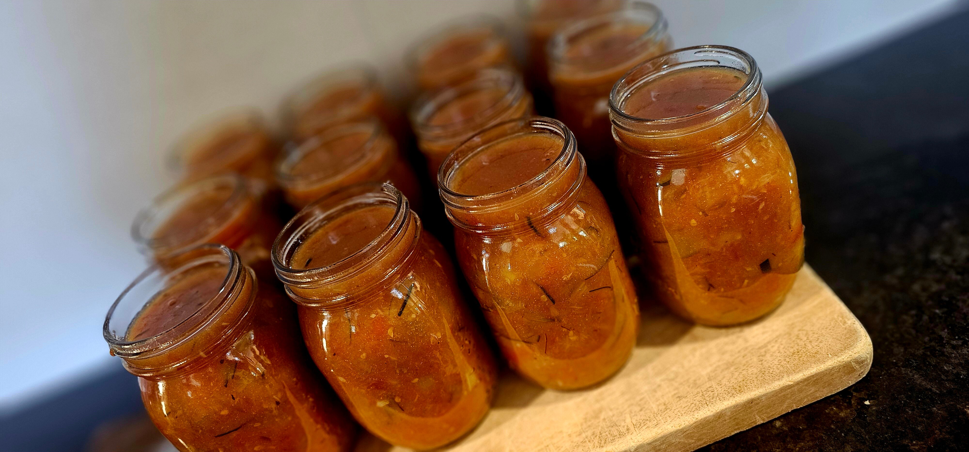 Board with relish jars on it full of red coloured relish