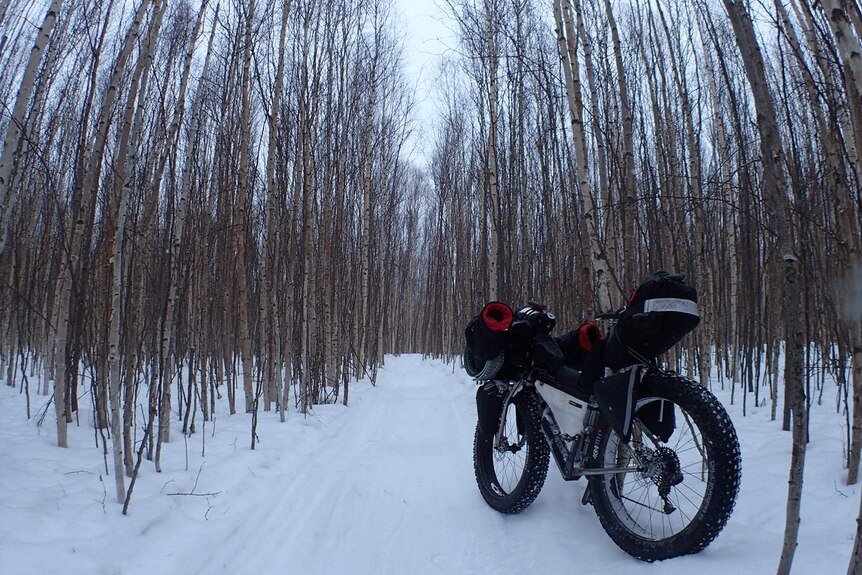 Ice trekker Troy Szczurkowski with his bike in the snow
