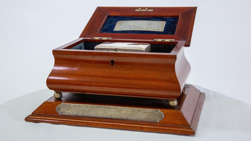 A wooden box containing a smaller, silver box that holds an important relic of Australian sport