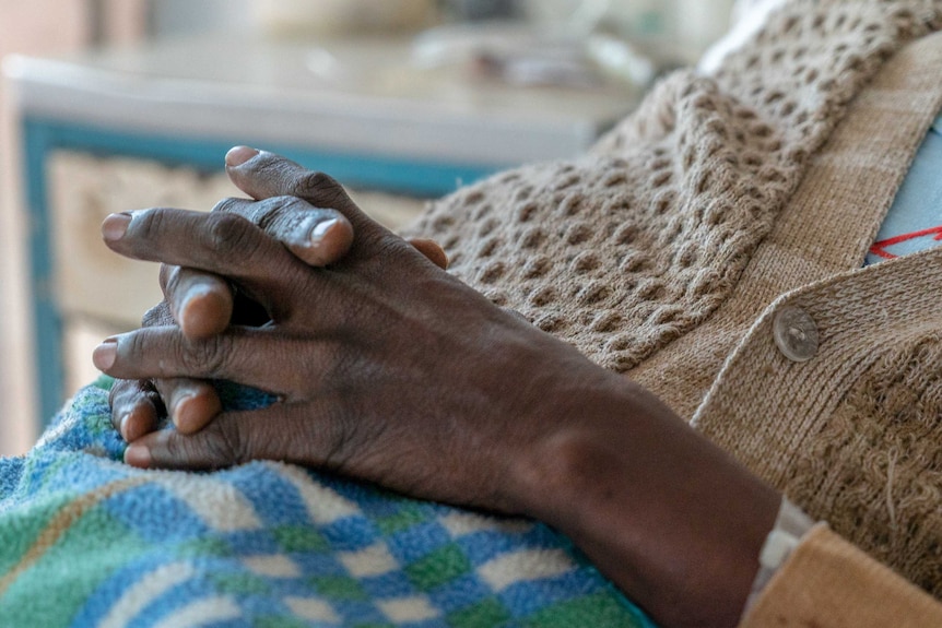 A woman's hands clasped on her stomach