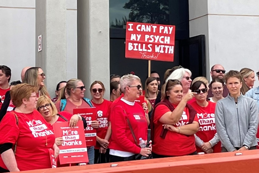 A group of people wearing red t-shirts holding a sign 