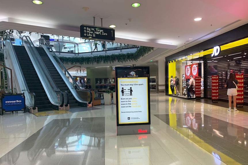 Near-empty mall and sign of coronavirus information at Westfield Garden City shopping centre in Brisbane.