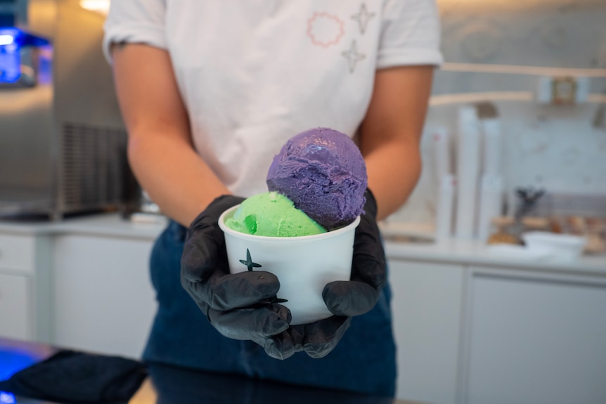 Girl holding a cup of colourful ice cream.