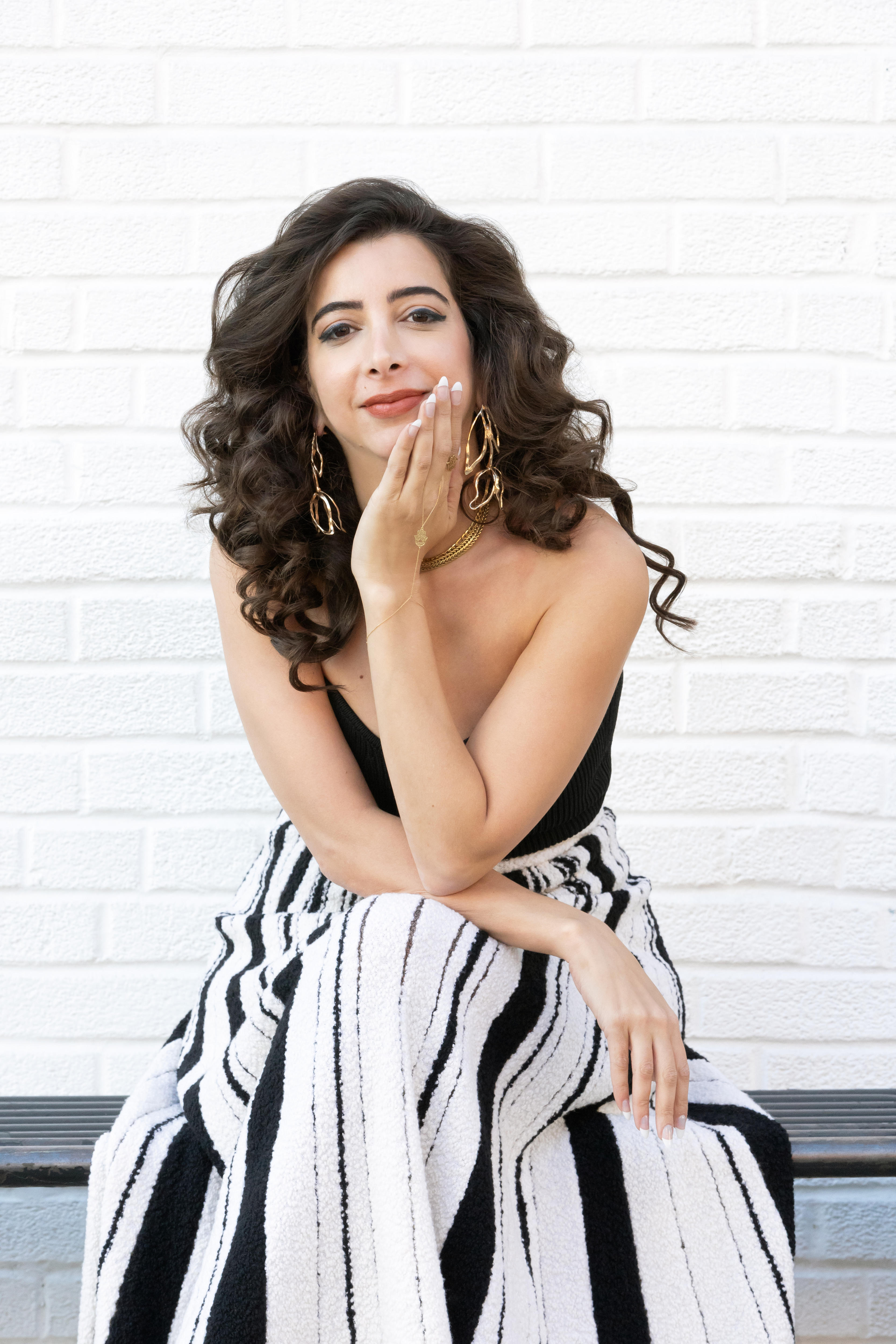 Portrait of a middle-aged Arab woman with long brown thick hair, who is wearing a long black and white dress