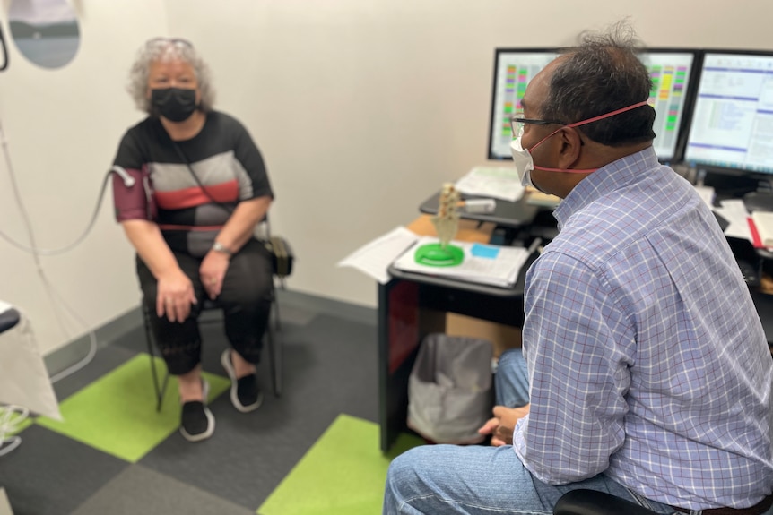 A patient hooked to a machine speaks to a doctor.