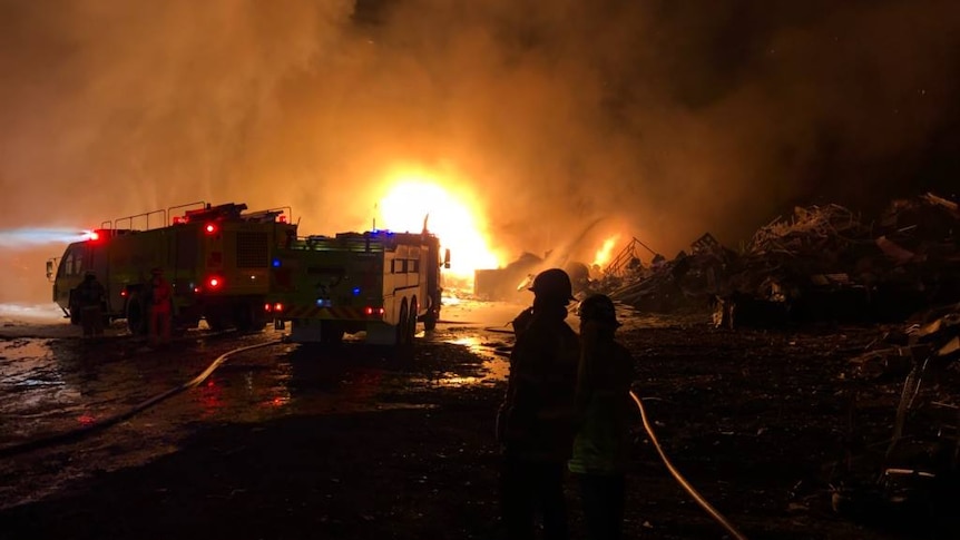 Firefighters are silhouetted against a fire.