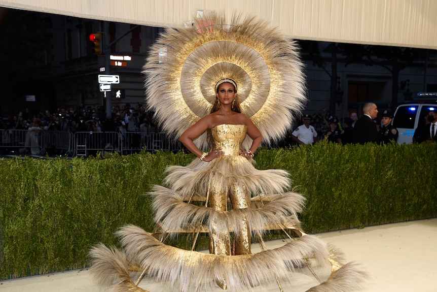 Iman in a golden fringe dress and headdress.