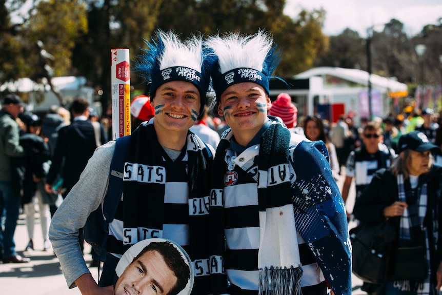 Two Geelong fans smile as they stand for a photo outside the MCG.