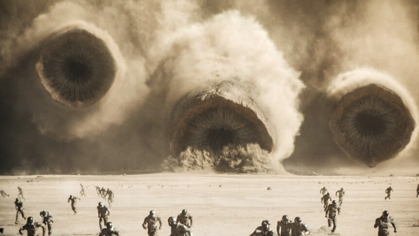 An image of a desert in the background are three large worm like creatures, in the foreground people are running away