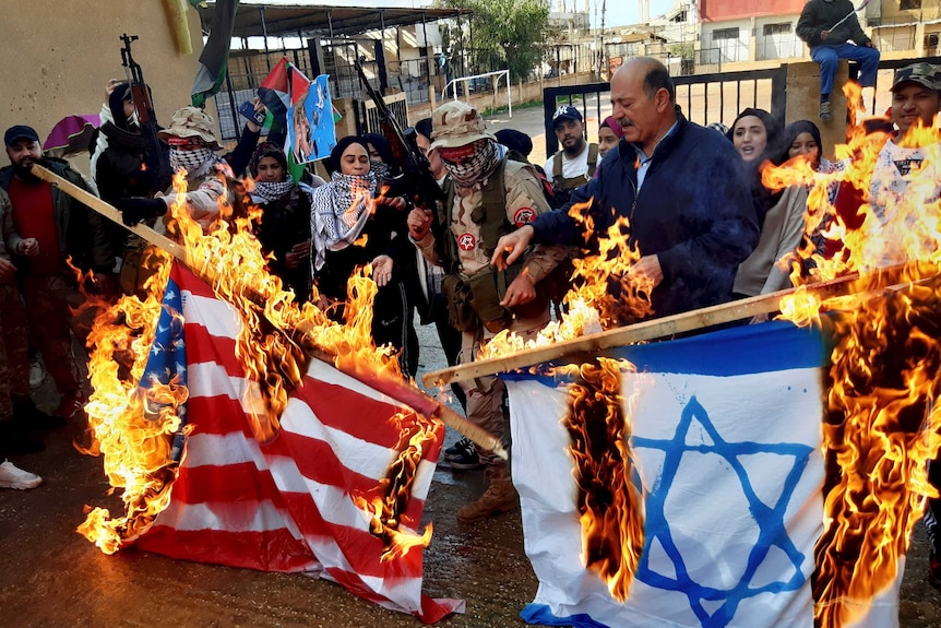 Palestinian gunmen and civilians burn the U.S. and the Israeli flags.