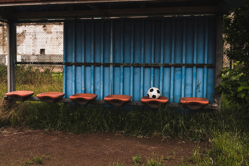 A neglected sports bench with a soccer ball