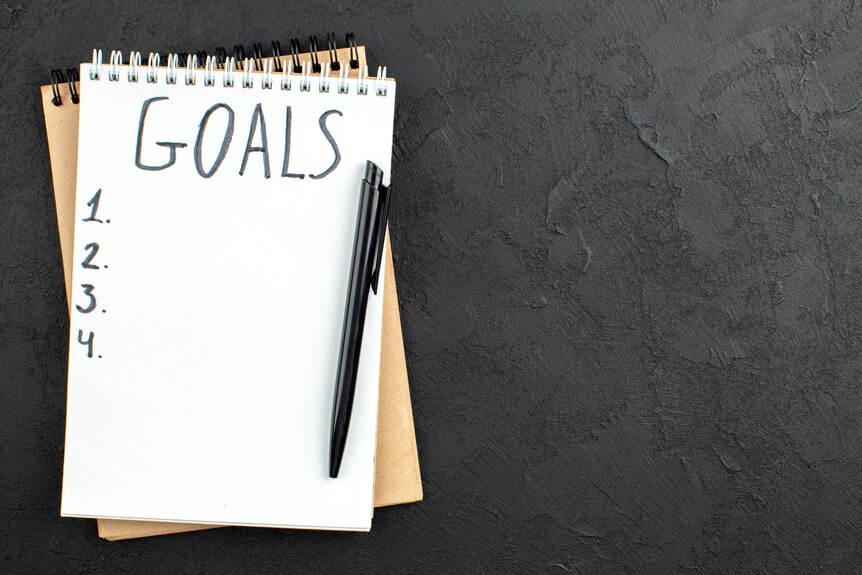 A notepad and pen with the word Goals written on top as a heading