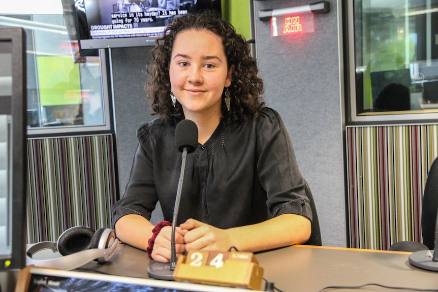 A 17-year-old high school student sitting in a studio in front of a microphone