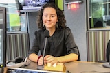 A 17-year-old high school student sitting in a studio in front of a microphone