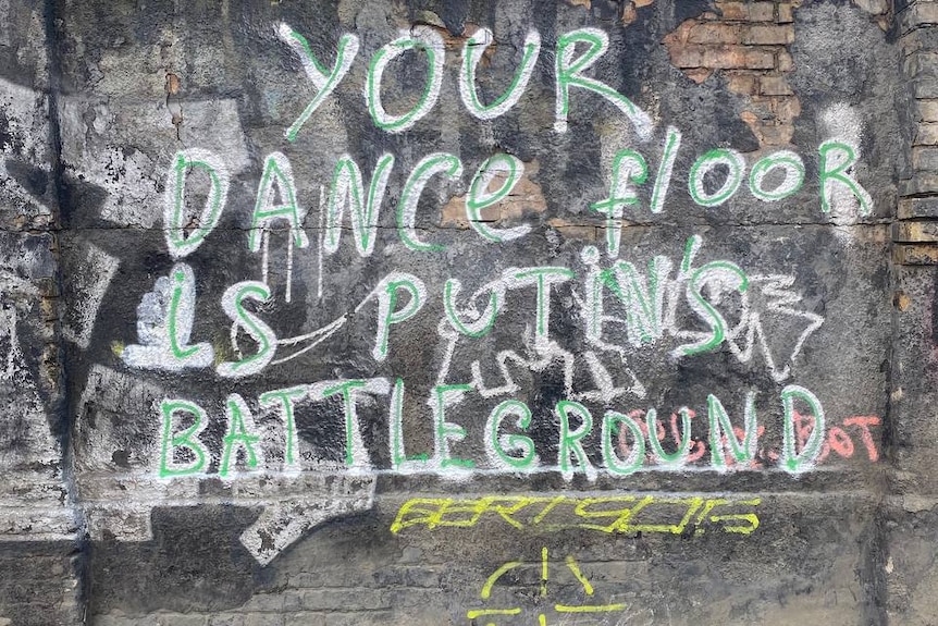 Graffiti on a wall in Kyiv outside a nightclub saying "your dancefloor is Putin's battleground". 