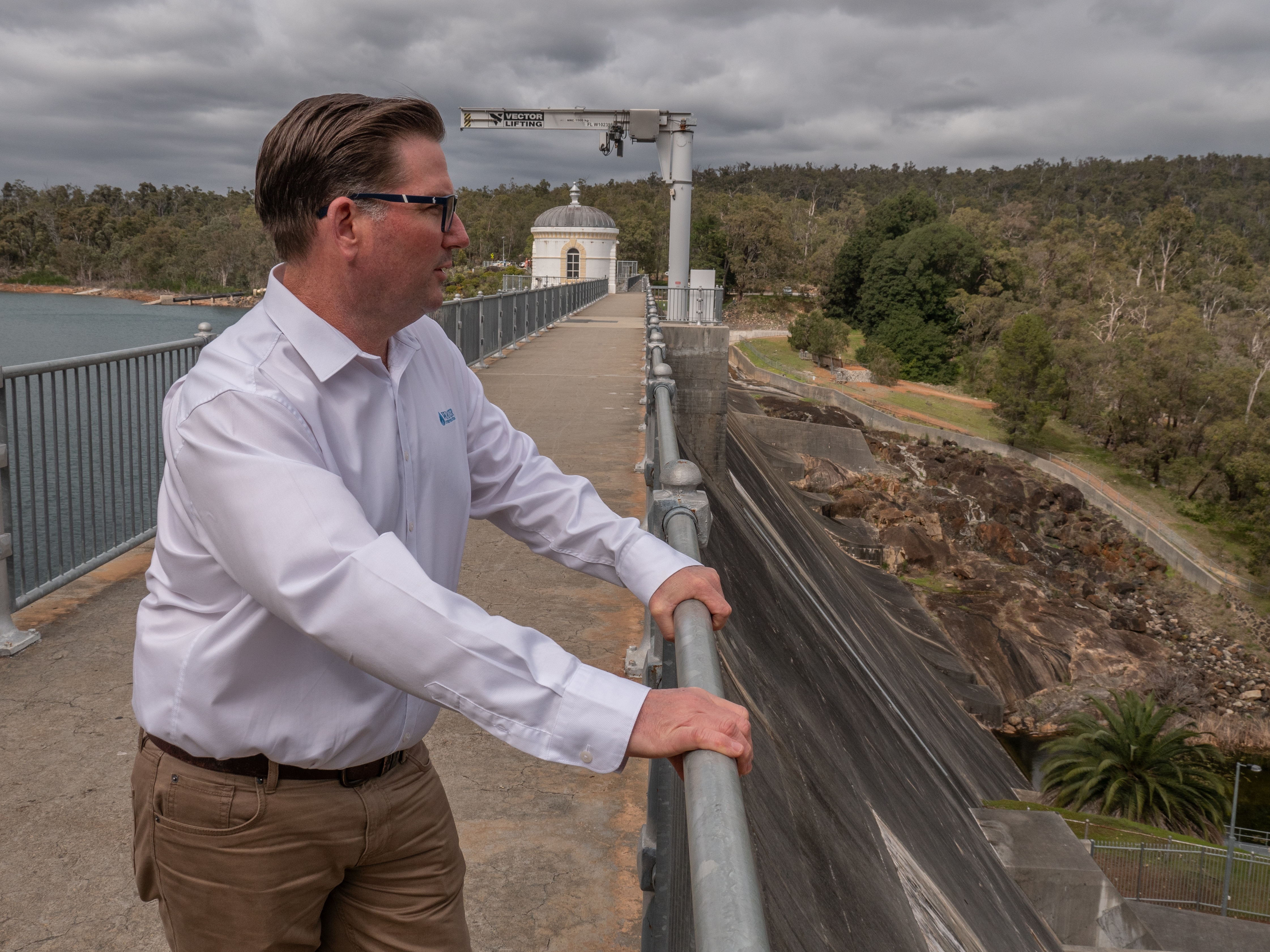 man stands on dam wall looking over