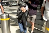 A woman charged over a hit and run in Melbourne leaves court with her face covered with a coat.