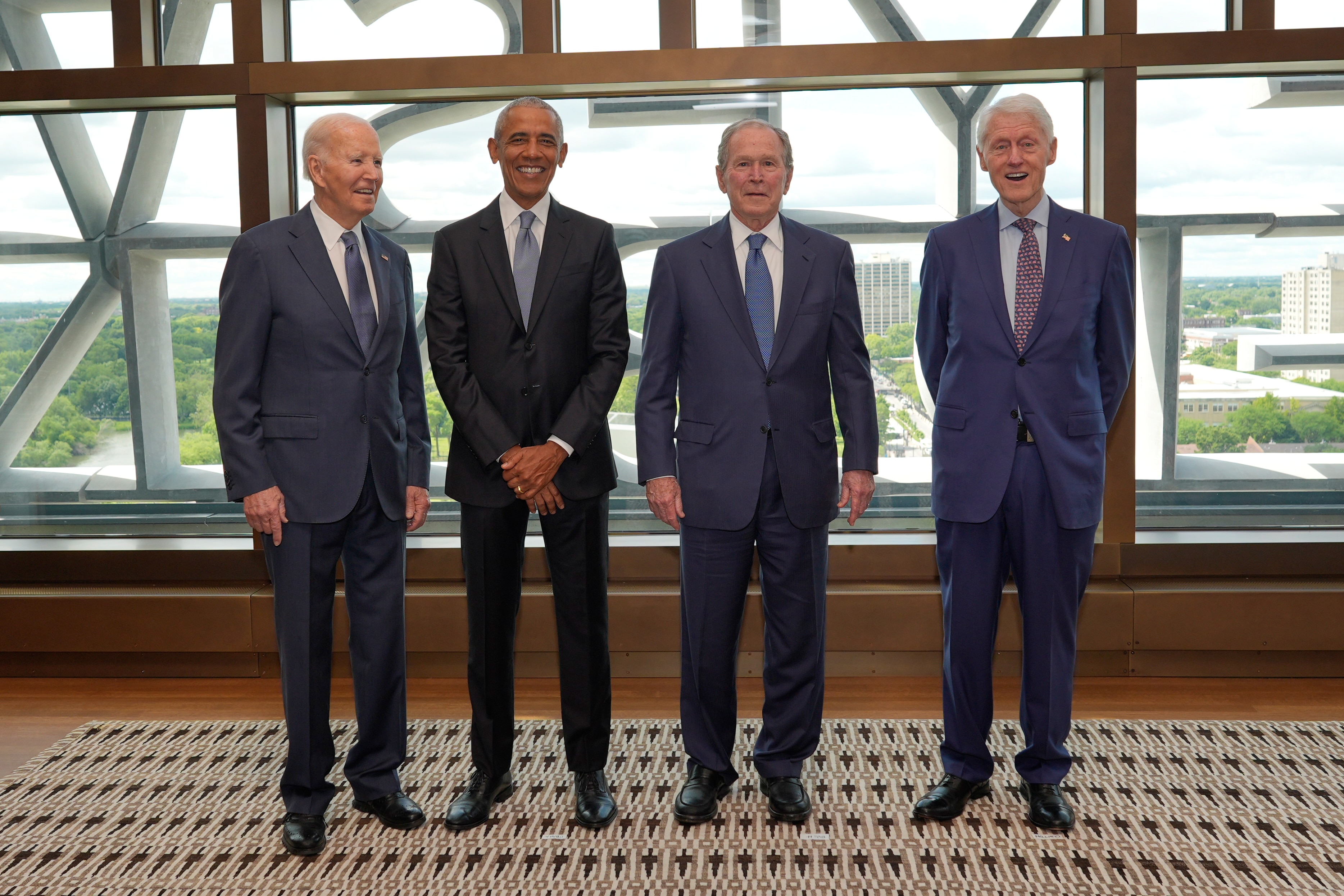 Joe Biden, Barack Obama, George W Bush and Bill Clinton in suits stand side by side. All smiling.