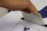 hand placing a vote in a ballot box