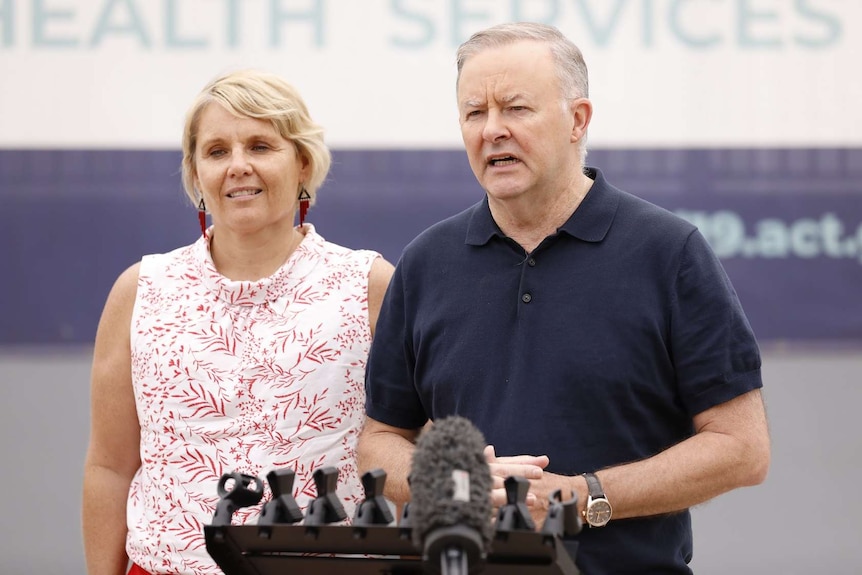 A woman and a man stand beside a podium