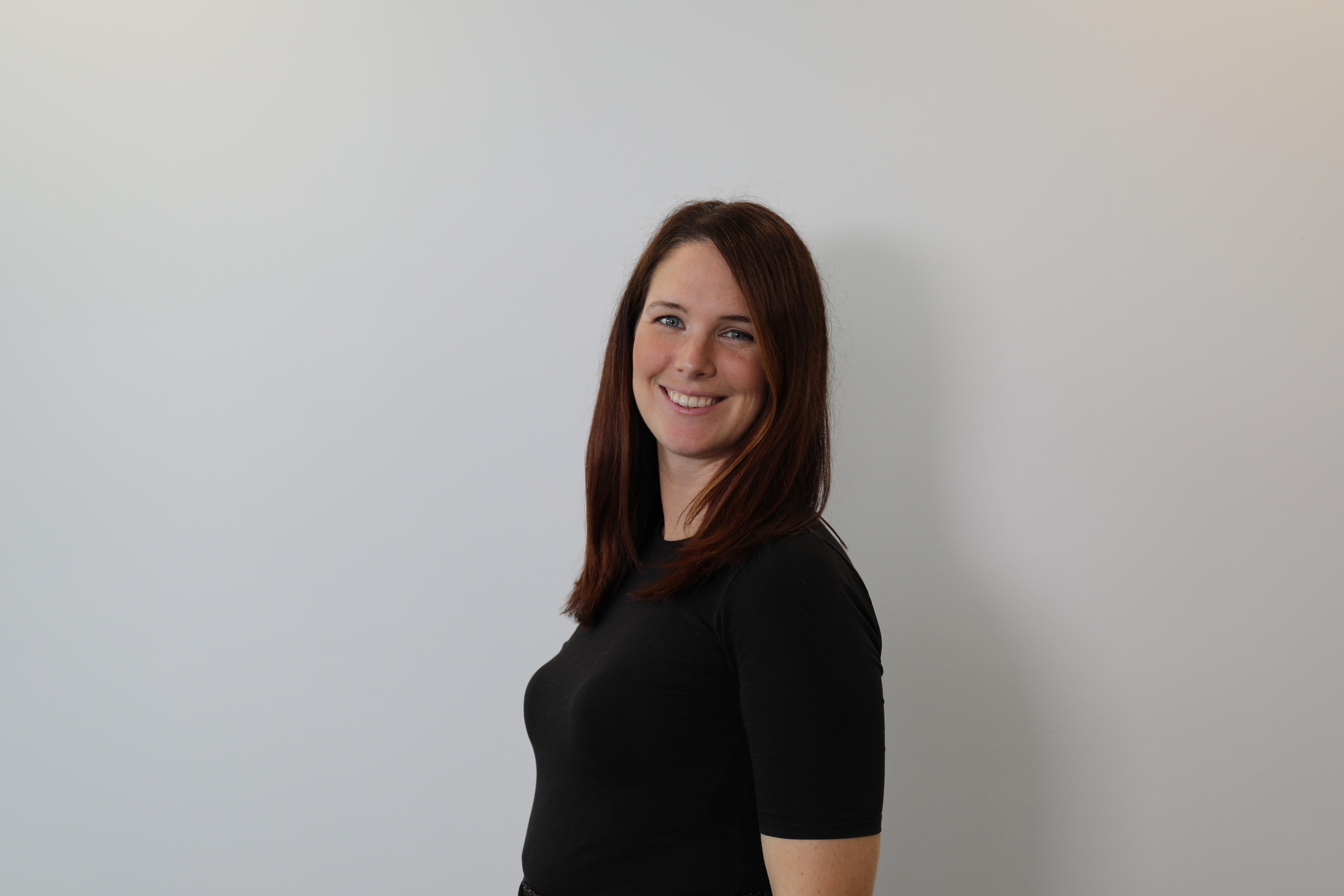 A woman in a black shirt with dark hair smiles at the camera.