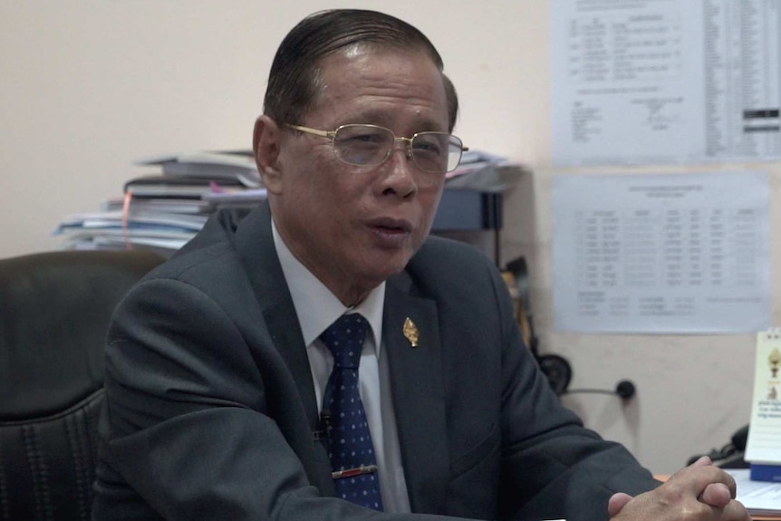 Sok Ey San sits at his desk