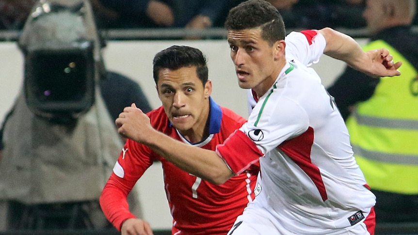 Voria Ghafouri challenges for a ball with Chile's Alexis Alejandro Sanchez.