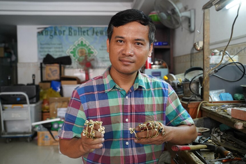 Thoeun Chantha poses with some of his pieces in his hands at Angkor Bullet Jewelry workshop