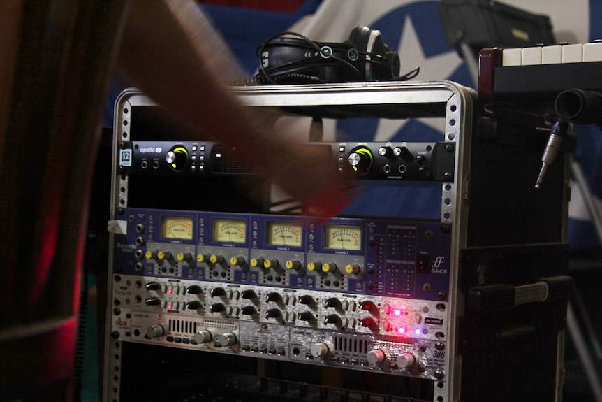 A hand adjusting the volume on a speaker playing the new Gurrumul album.