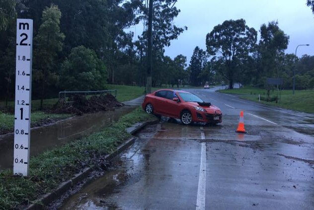 A car was caught in floodwaters on Rafting Ground Road near Brookfield in western Brisbane.