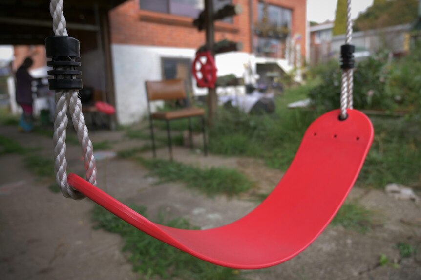 A close up of a child's red swing in a foster carer's backyard