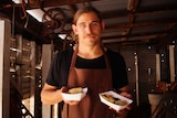 WA Chef Paul Iskov holding two "street food"-style meals he has created using native foods.