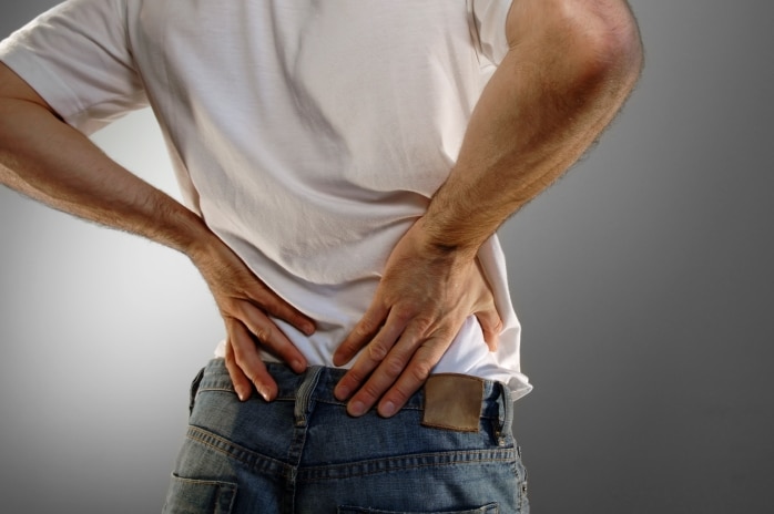 Man with his hands on his lower back in pain.