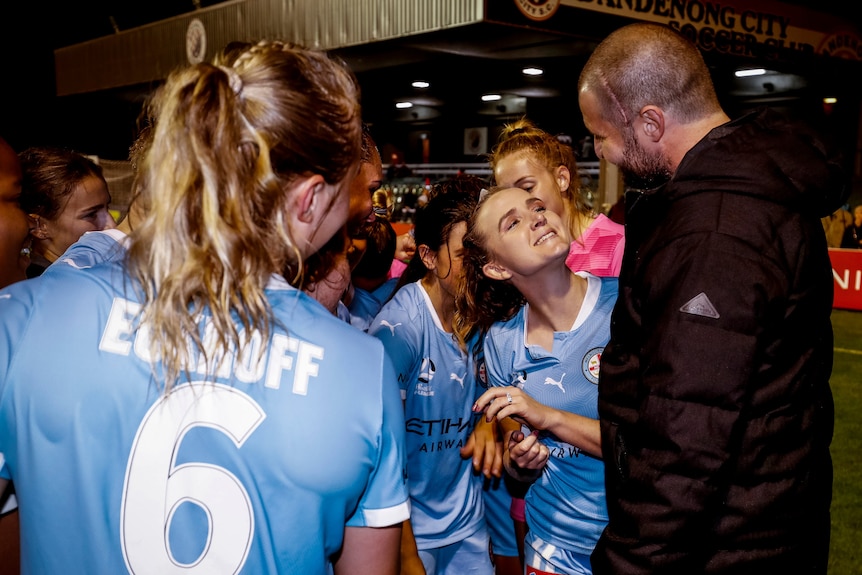 A W-League player smiles up at her partner with an engagement ring on her finger.