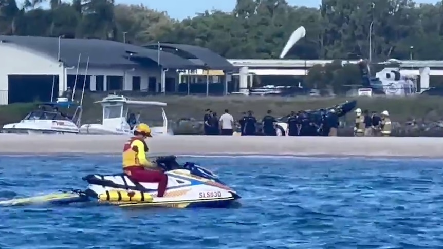 View of scene of helicopter crash scene from the water near Sea World, jet ski rider in the foreground