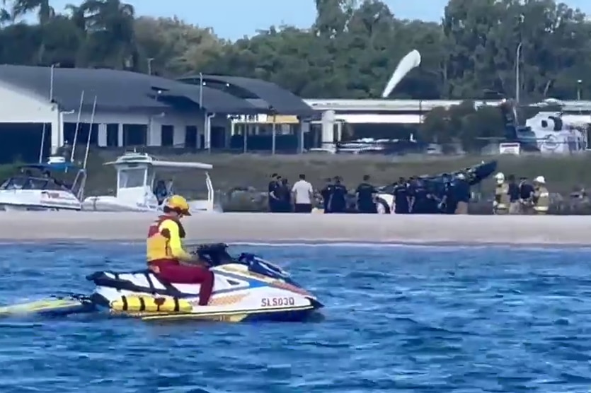 View of scene of helicopter crash scene from the water near Sea World, jet ski rider in the foreground