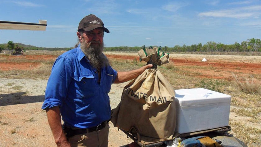 Taffy Abbotts collects mail bag on Kimberley mail run at airstrip with plane tip visible
