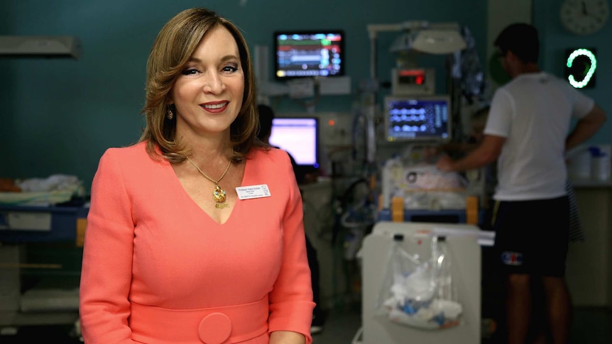 woman in a hospital suite with glowing machinery in the background