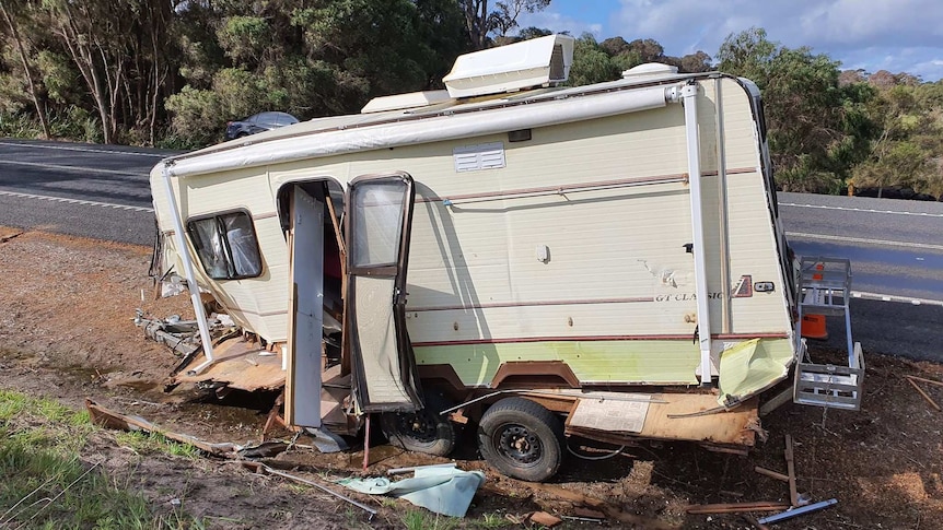 A destroyed caravan next to the roadside.
