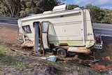 A destroyed caravan next to the roadside.