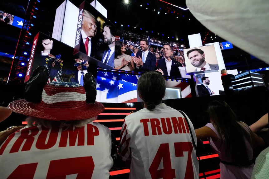 Delegates look up at a big screen with Trump and JD Vance clapping