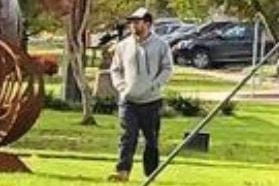 A blurry image of a man wearing a grey hoodie and a baseball cap