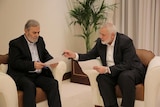 Two men sitting on chairs reading documents. 