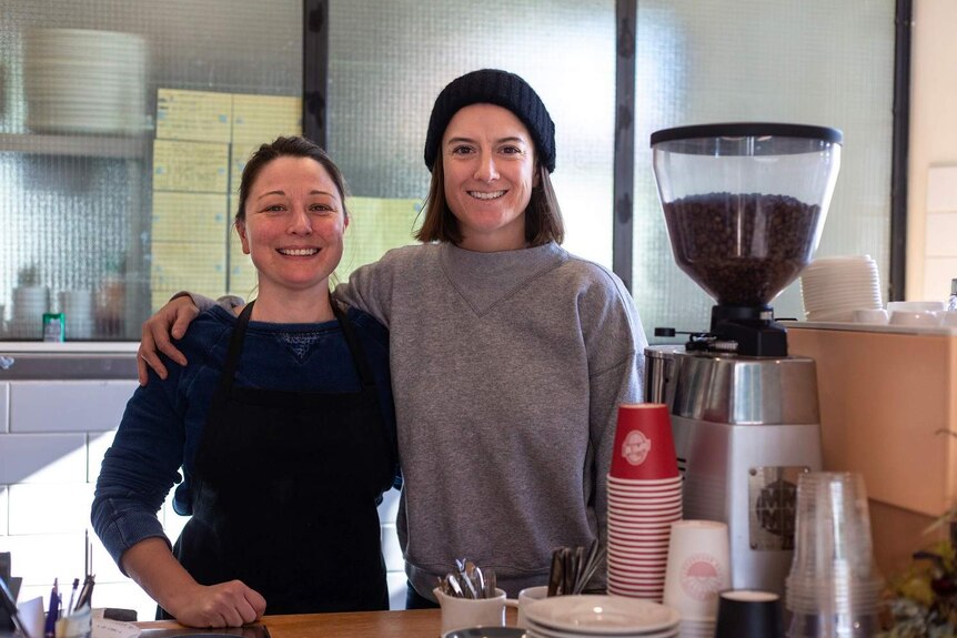 Two cafe owners, Candice and Susannah, stand behind a coffee machine at Jessie's Girl cafe in Brisbane, taken on 24th July 2017