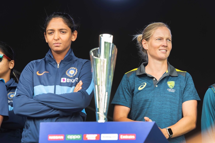 Two women pose with the T20 World Cup